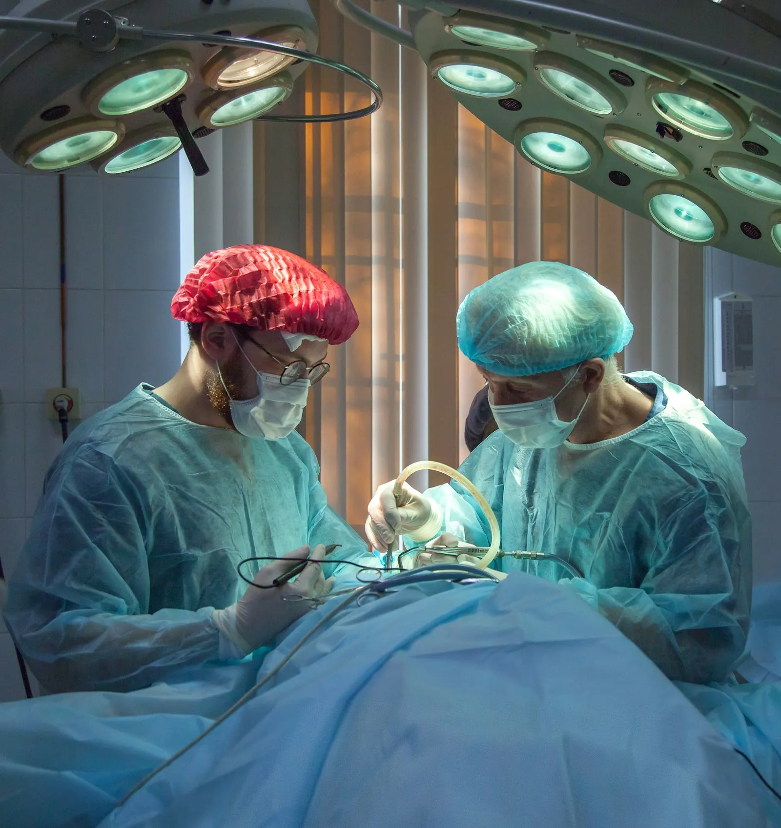 Surgical team in masks and caps under operating lights